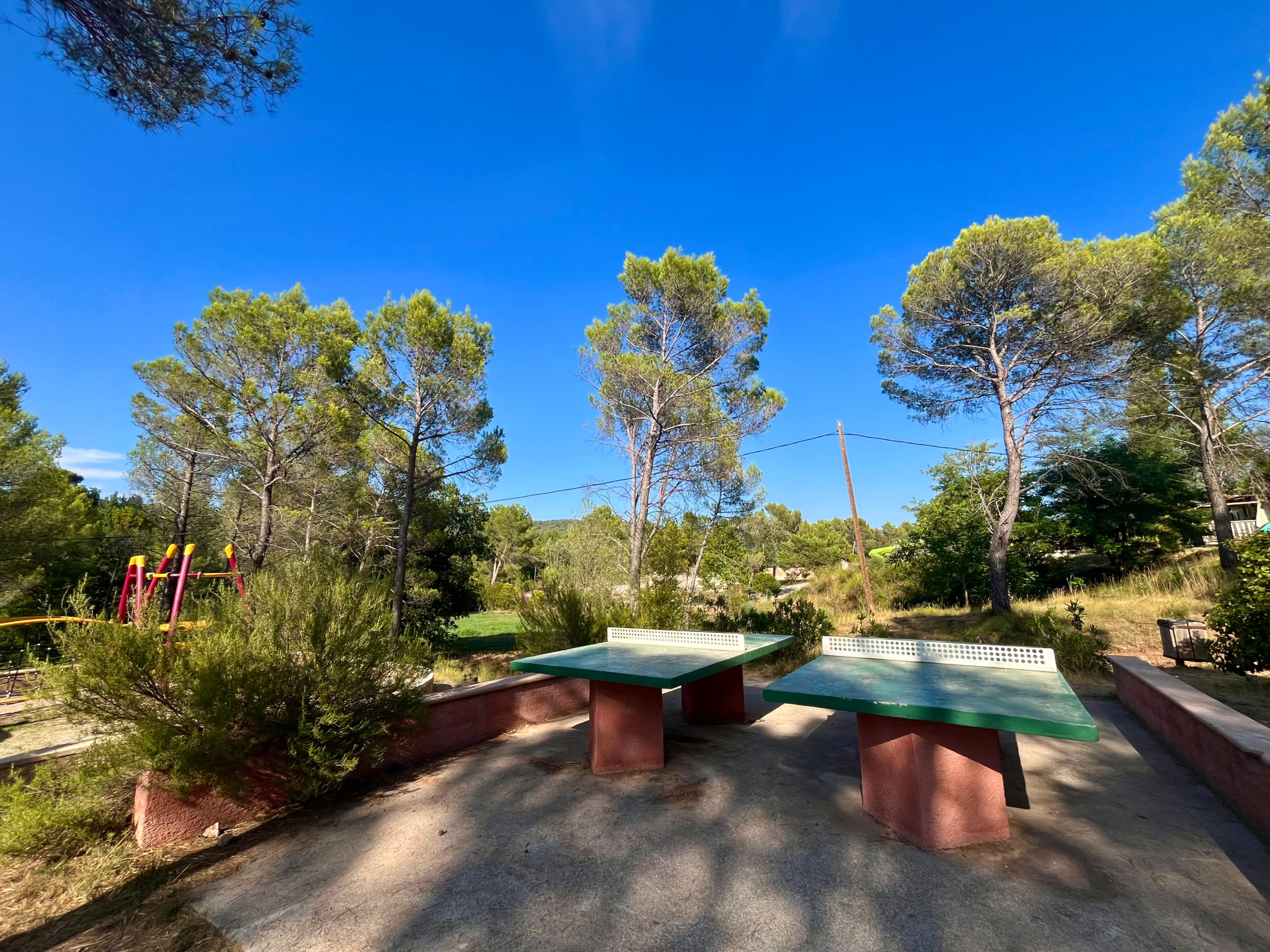 Zone de loisirs avec tables de ping-pong et aire de jeux enfants dans le camping du Var.