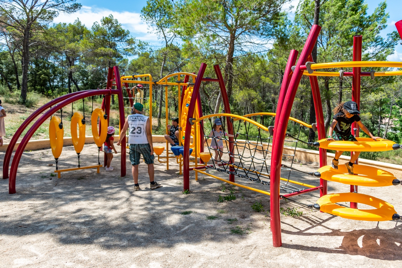 Enfants jouant sur une aire de jeux moderne avec structures en rouge et jaune à Villecroze-les-Grottes