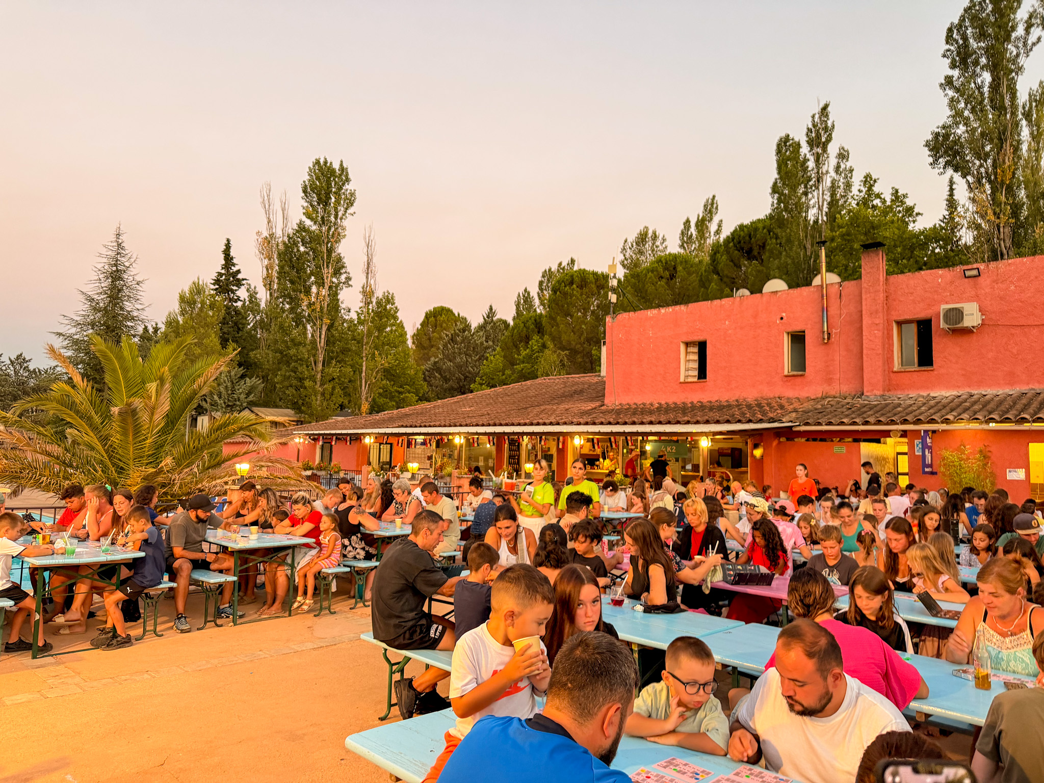 Animation enfants avec repas collectif en plein air devant bâtiment rouge au Var