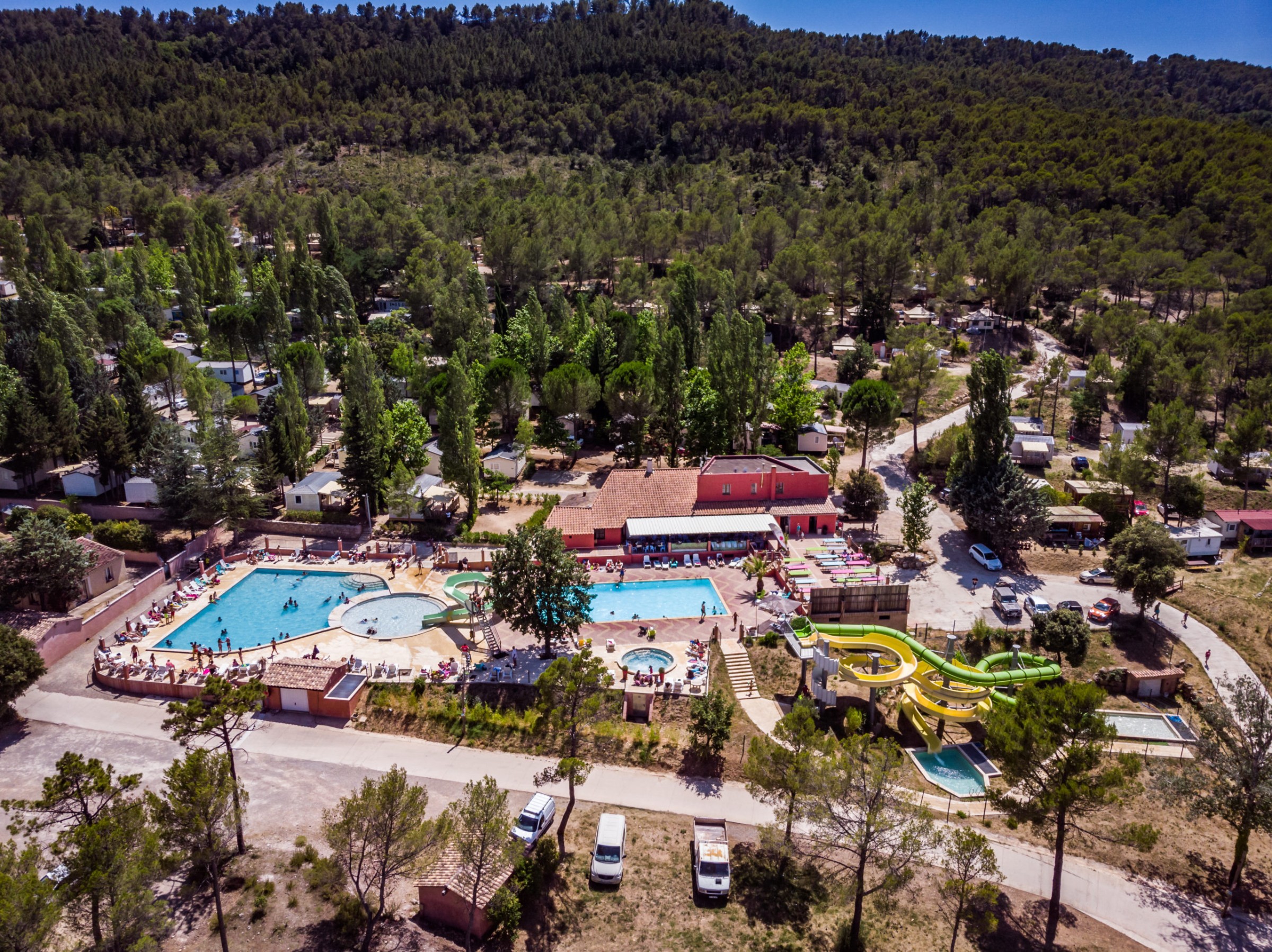 Vue aérienne du camping Les Cadenières avec piscines et installations dans les forêts du Var.