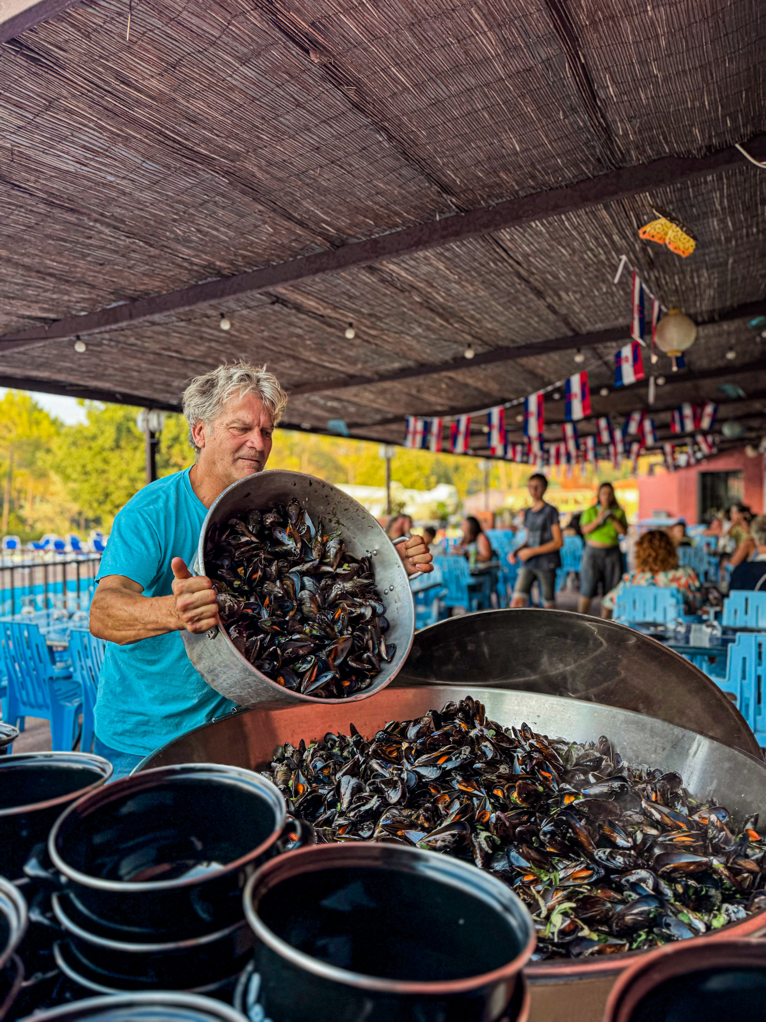 Chef préparant des moules lors d'une soirée gastronomique collective au camping du Var.