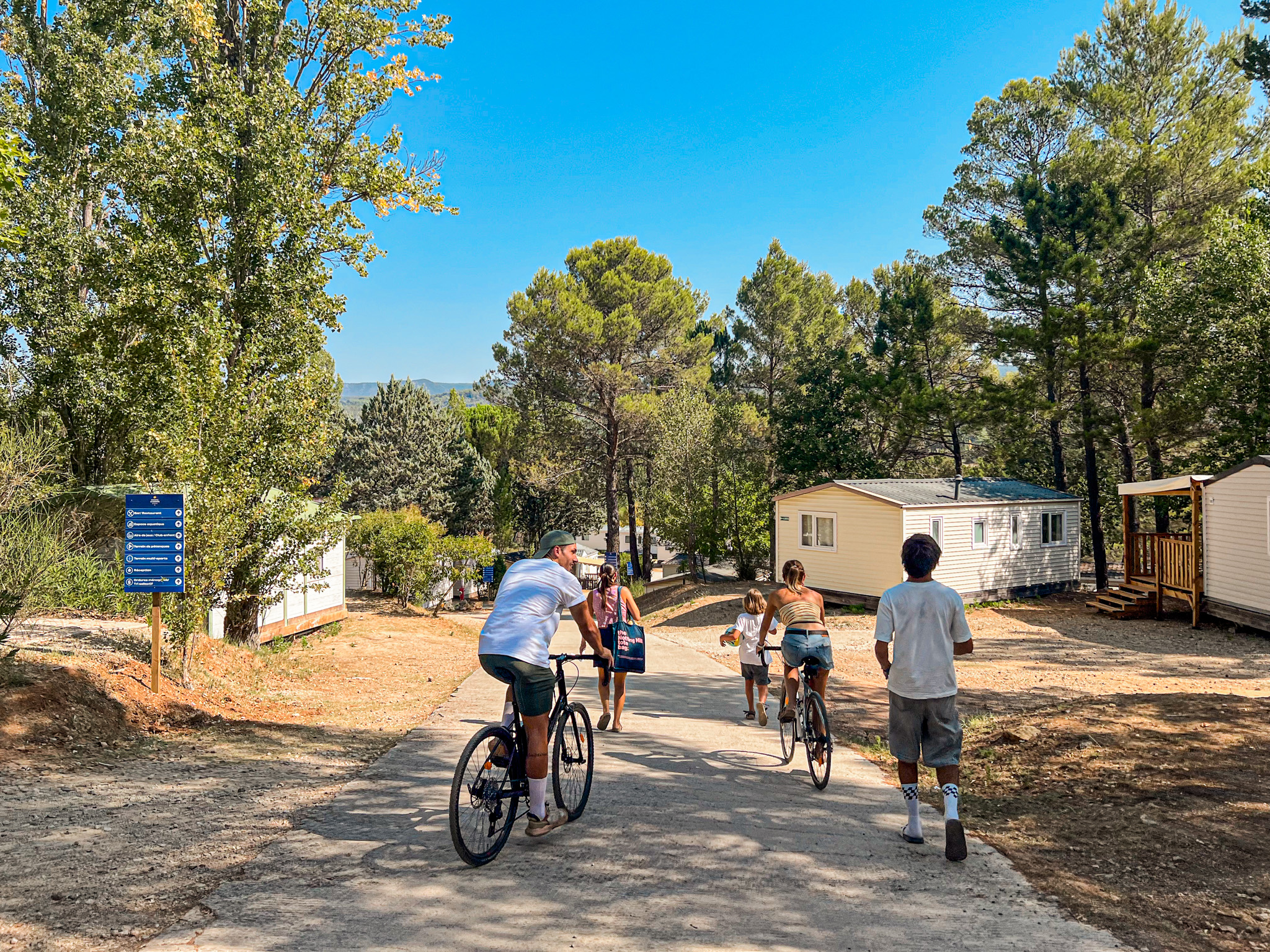 Emplacements de camping avec mobil-homes et famille à vélo sous les pins à Villecroze-les-Grottes