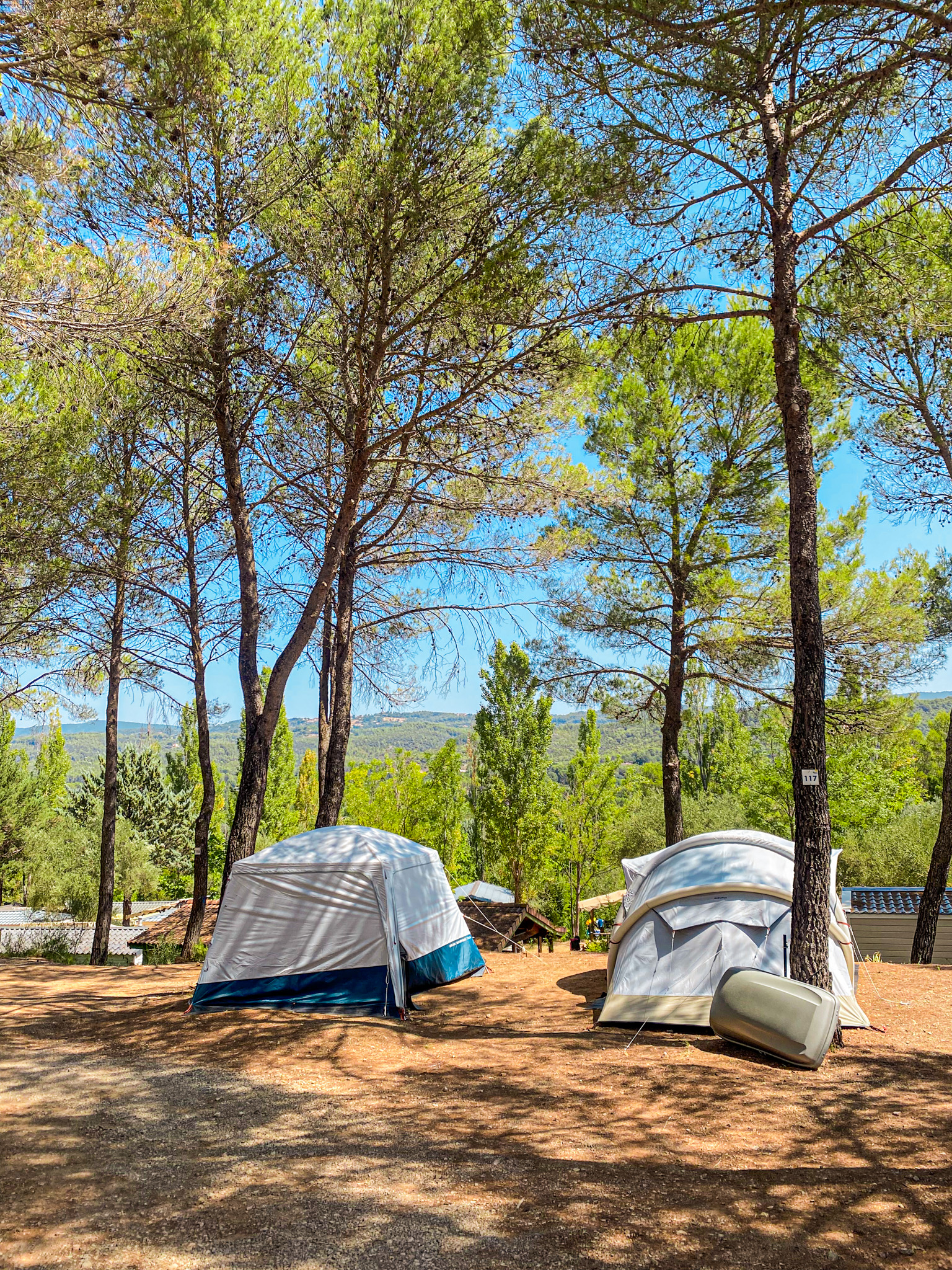 Emplacements de camping avec tentes sous les pins et paysage boisé à Villecroze-les-Grottes