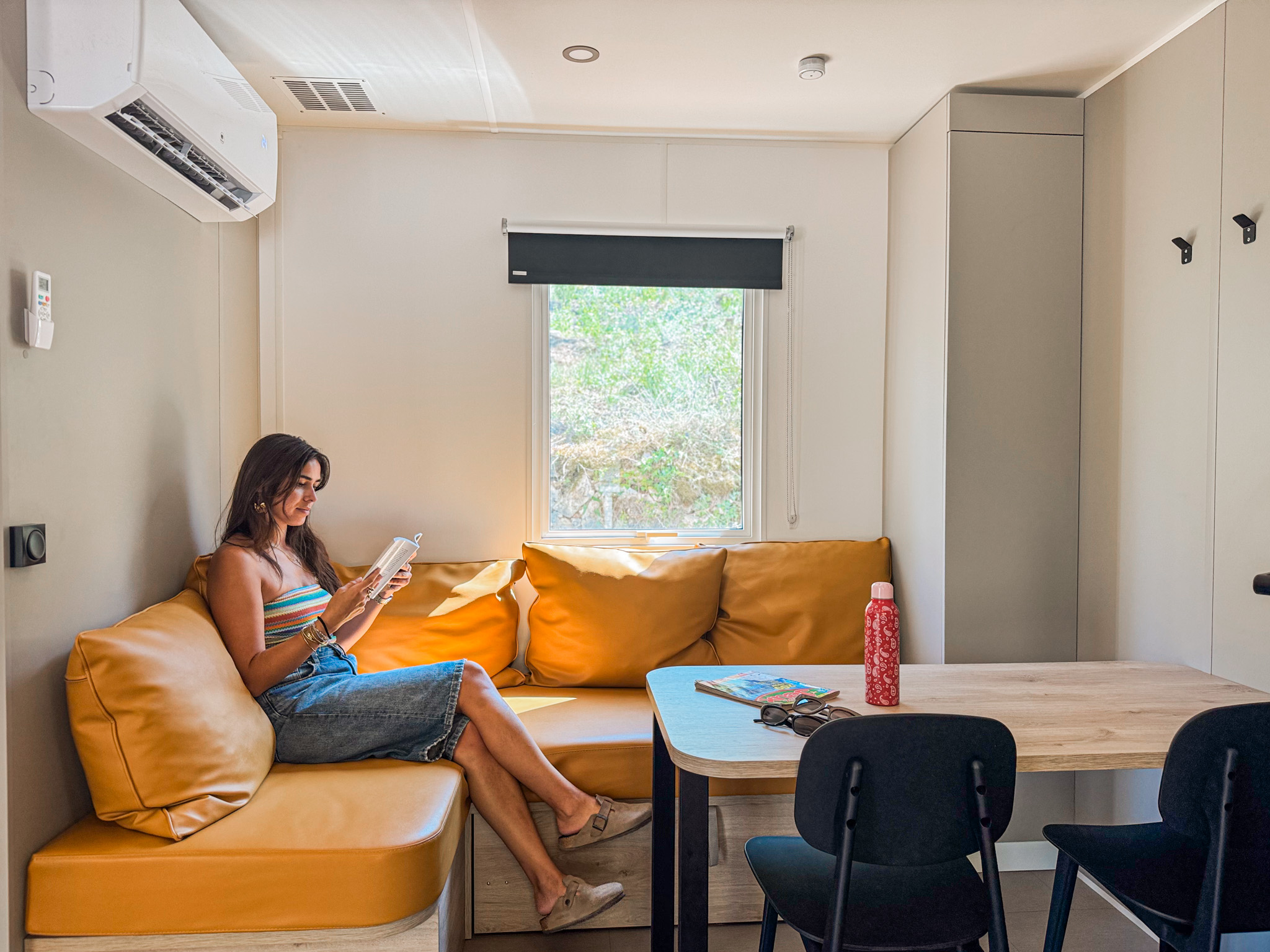 Intérieur confortable d'un mobil-home avec canapé orange et vue sur nature au Var.