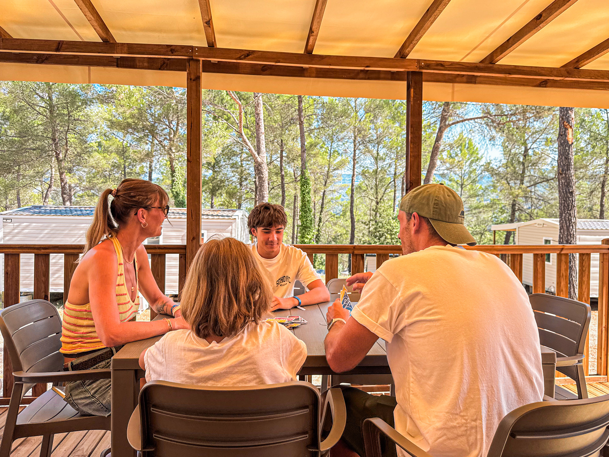 Famille réunie autour d'une table sous la pergola de leur mobil-home au Var