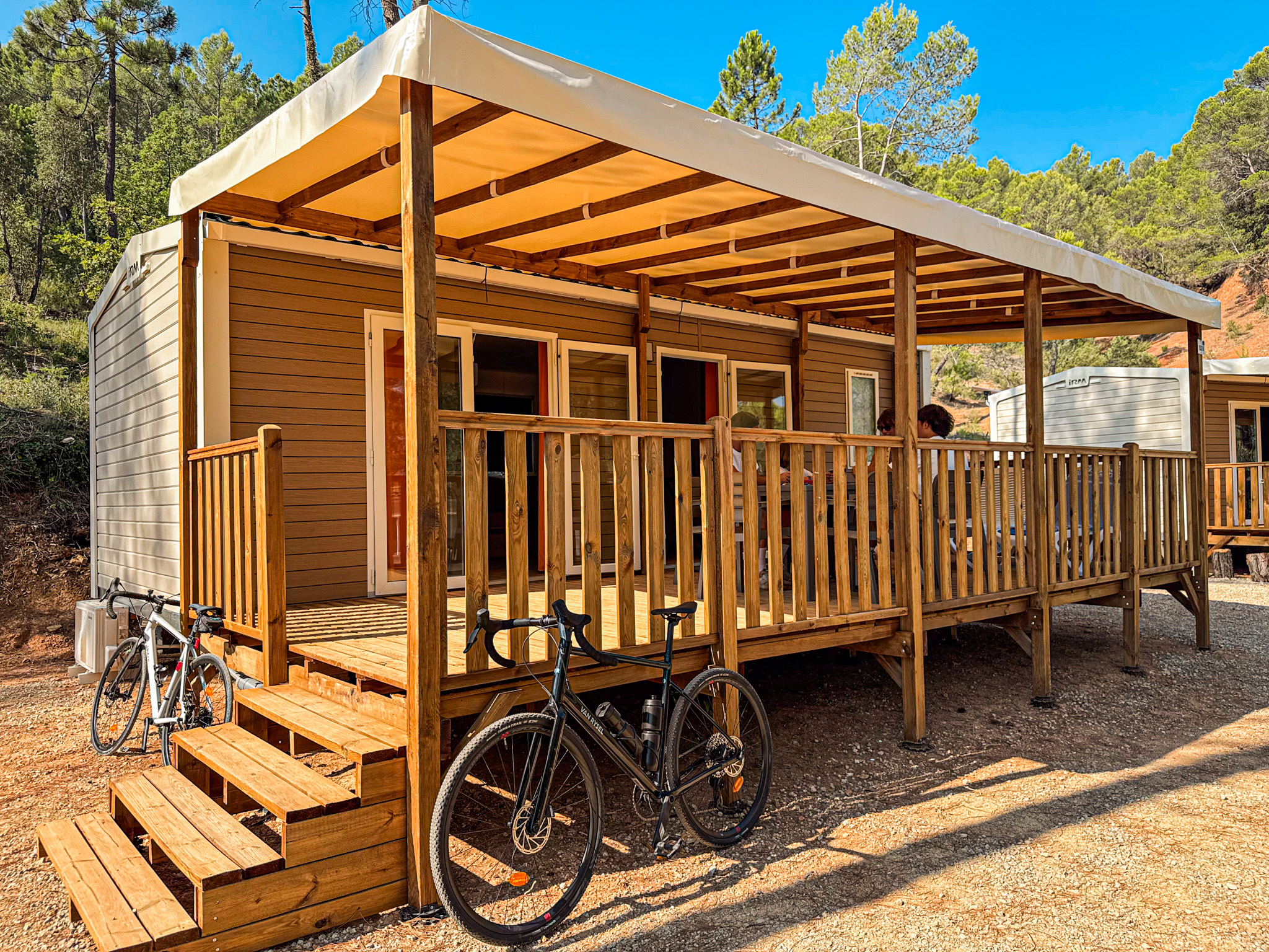 Mobil-home avec terrasse couverte et salon de jardin à Villecroze-les-Grottes, vélos garés devant
