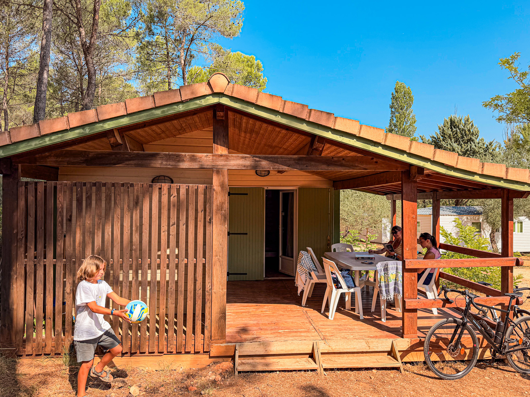 Mobil-home avec terrasse couverte, vélo et enfants jouant à Villecroze-les-Grottes