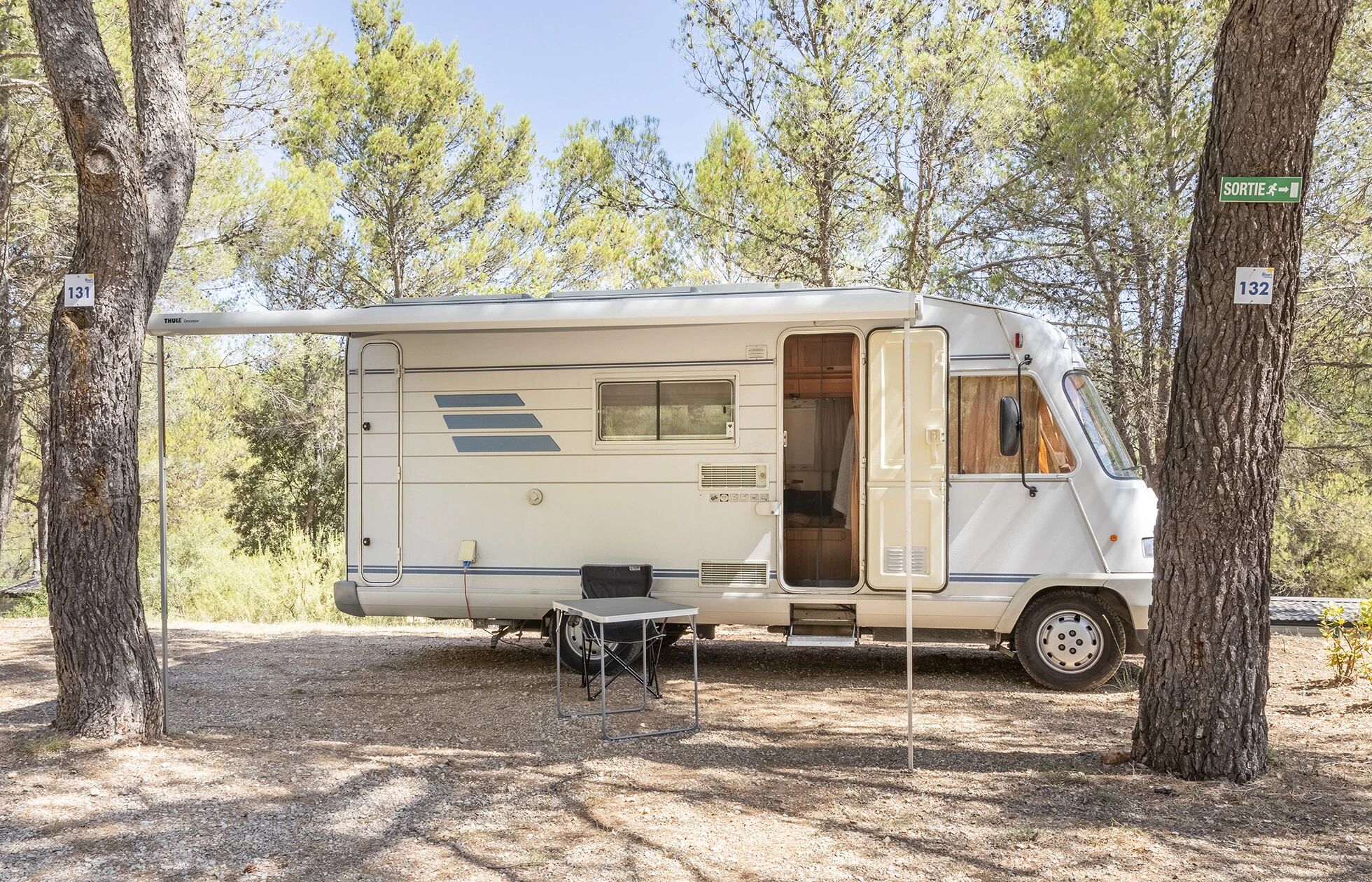 Mobil-home blanc stationné sur emplacement ombragé par les pins du Var.
