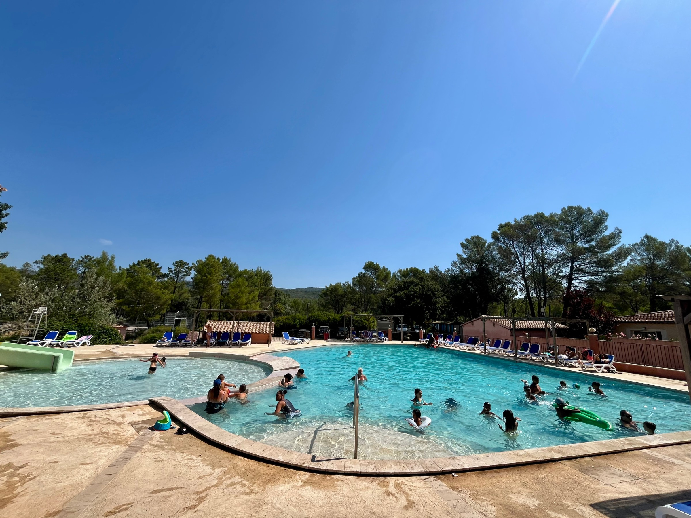 Piscine accueillante avec baigneurs et transats colorés à Villecroze-les-Grottes