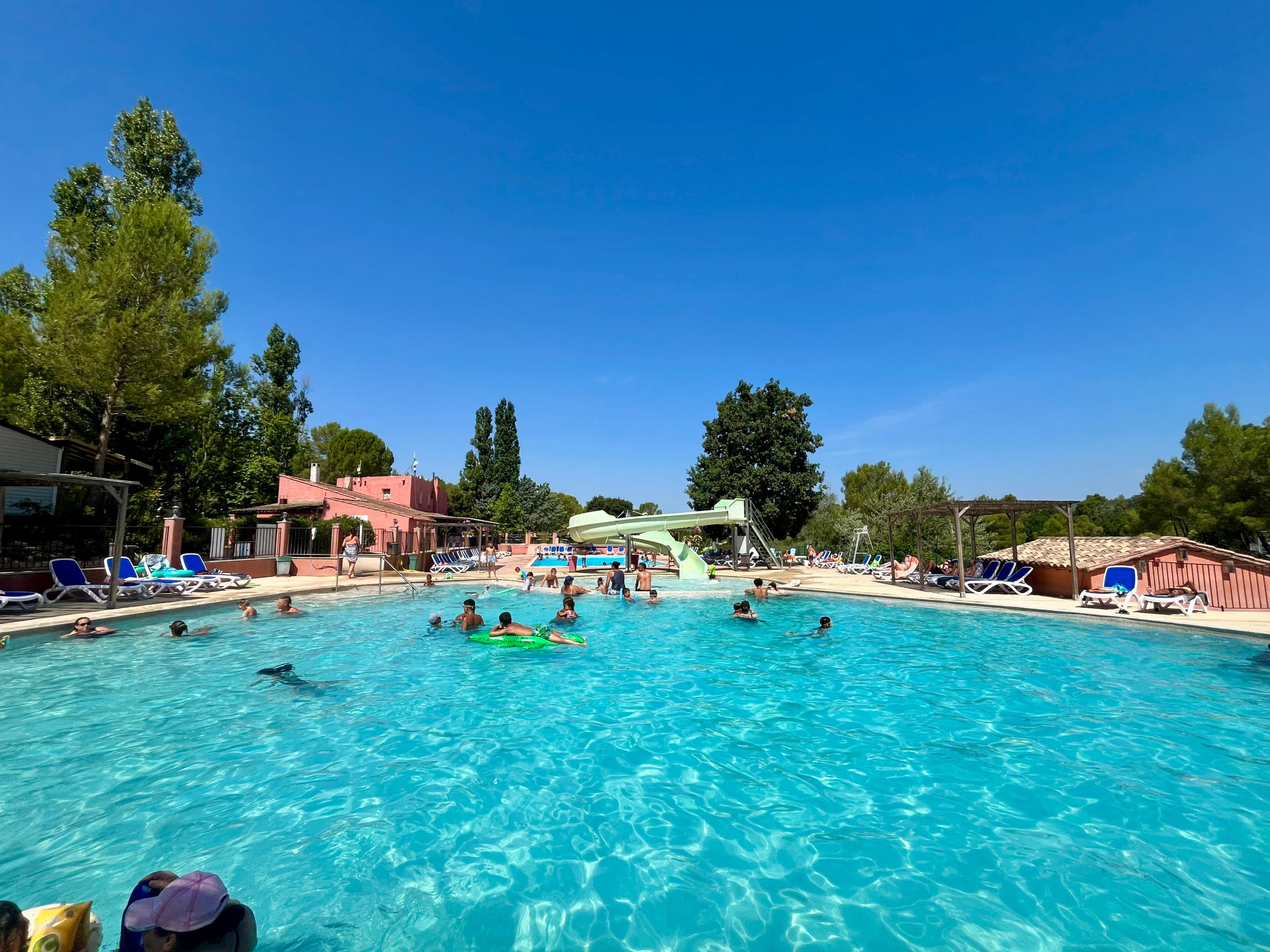 Grande piscine avec baigneurs et transats bleus au soleil à Le Var
