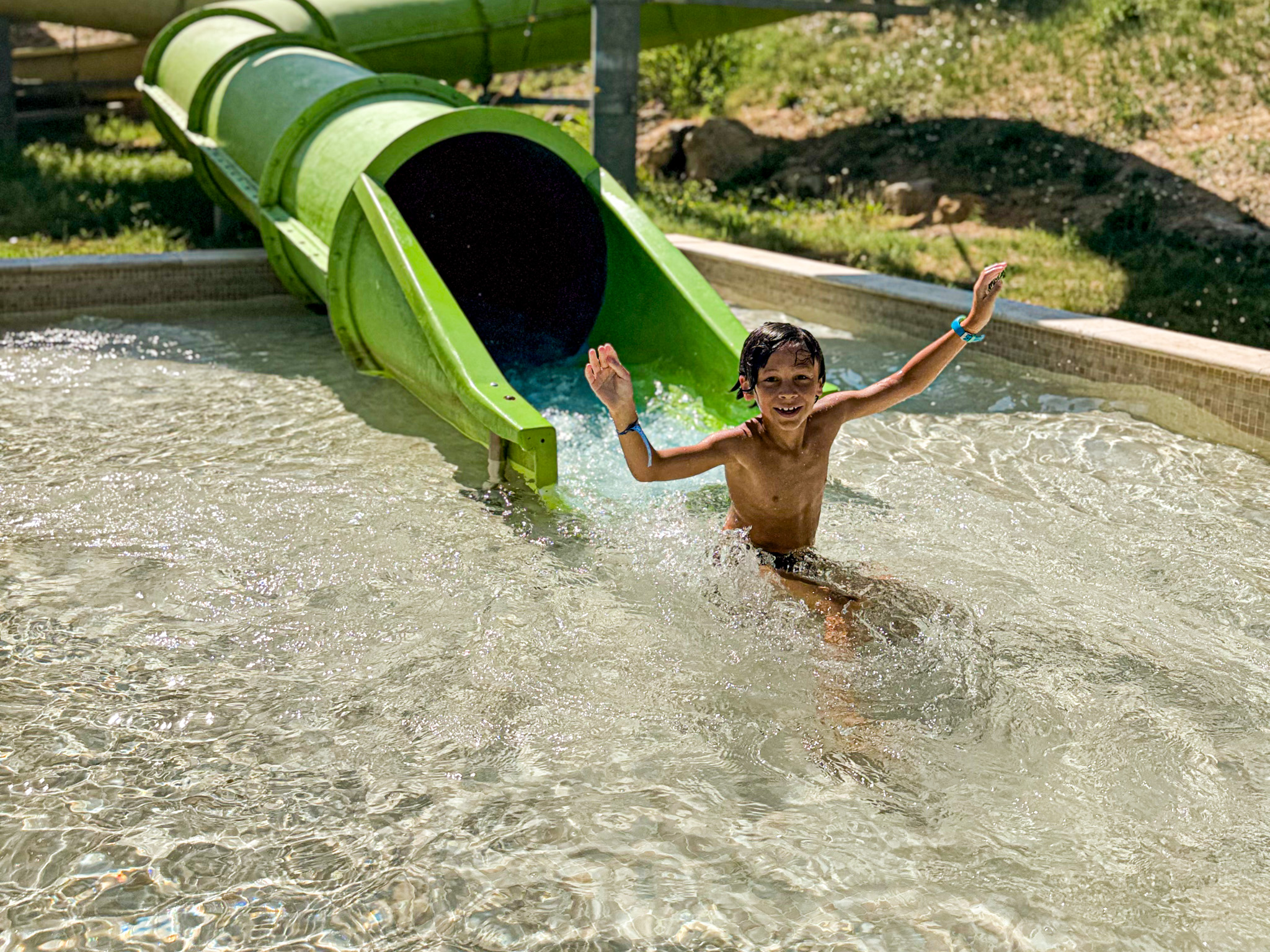 Enfant glissant joyeusement du toboggan aquatique dans la piscine à Villecroze-les-Grottes.