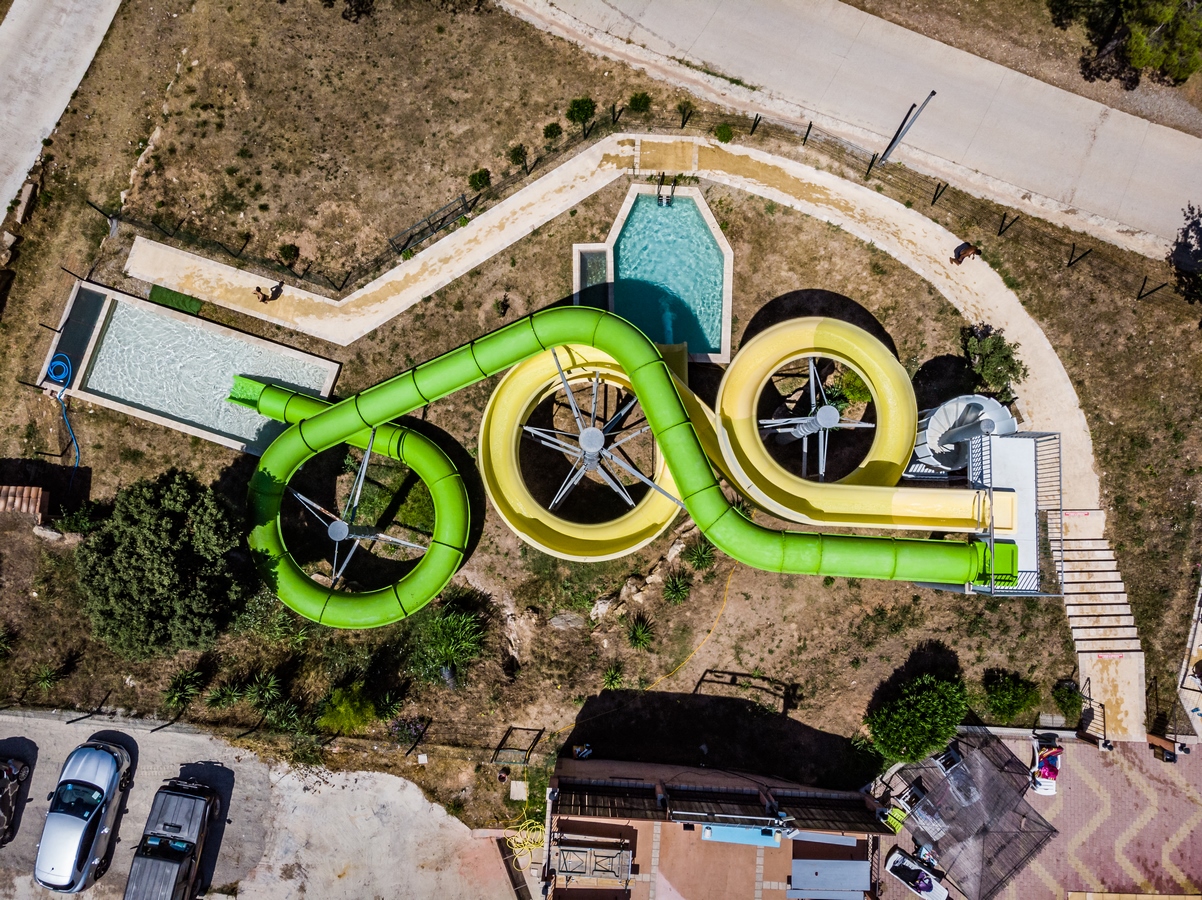 Espace aquatique avec toboggans géants verts et jaunes dominant les bassins du camping Le Var