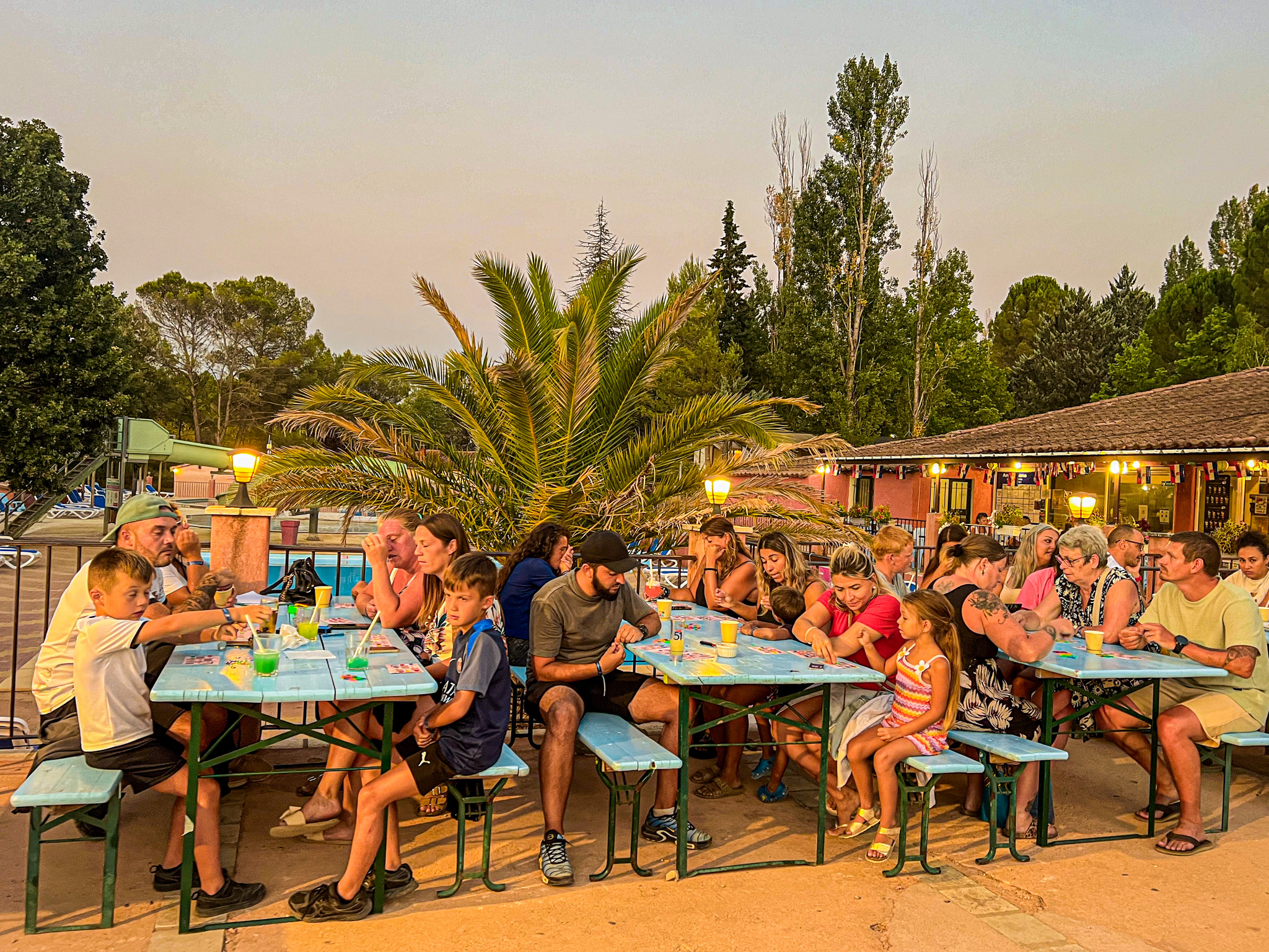 Familles déjeunant ensemble à des tables en plein air sous les palmiers à Villecroze-les-Grottes