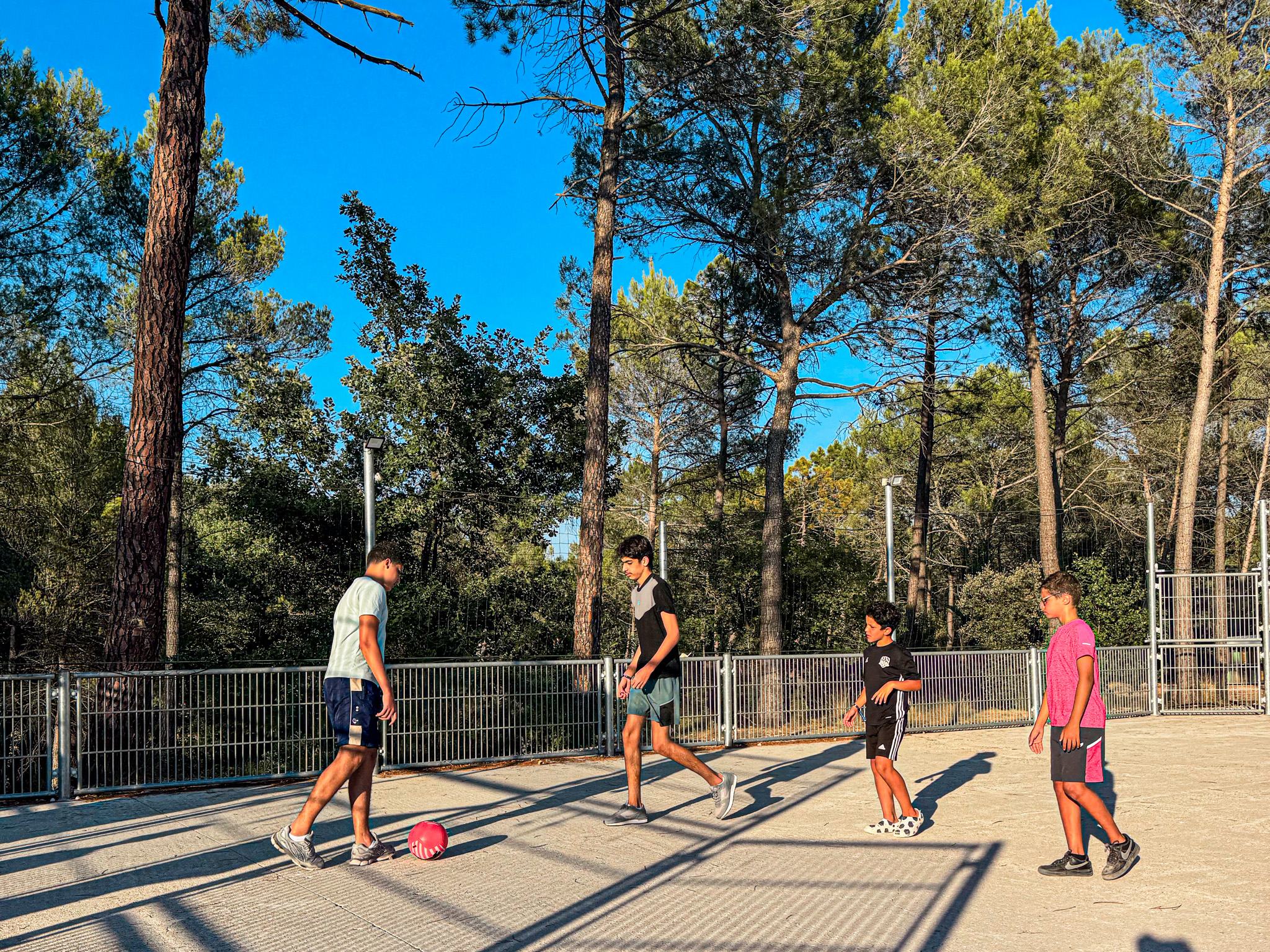 Groupe de jeunes jouant au football sur un terrain sportif du camping dans Le Var