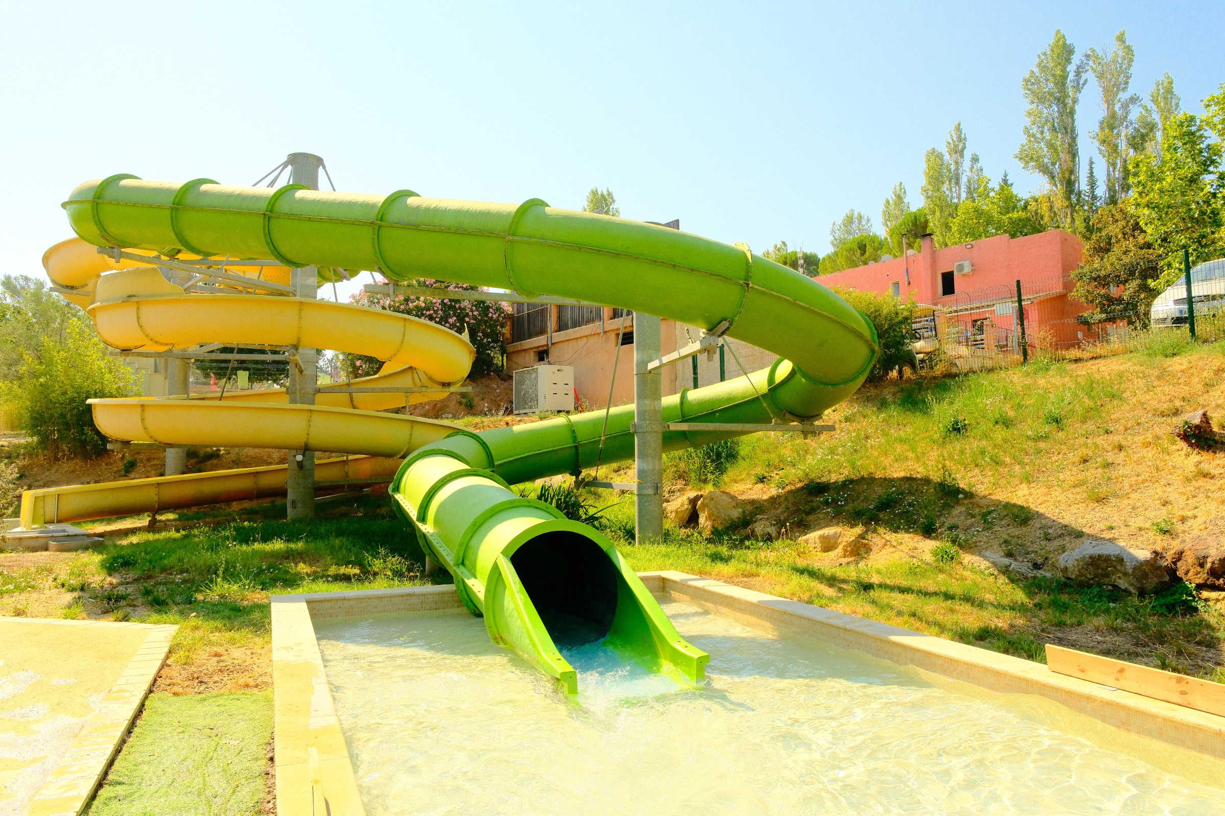 Toboggan géant vert avec enfants se baignant dans la piscine au Var.